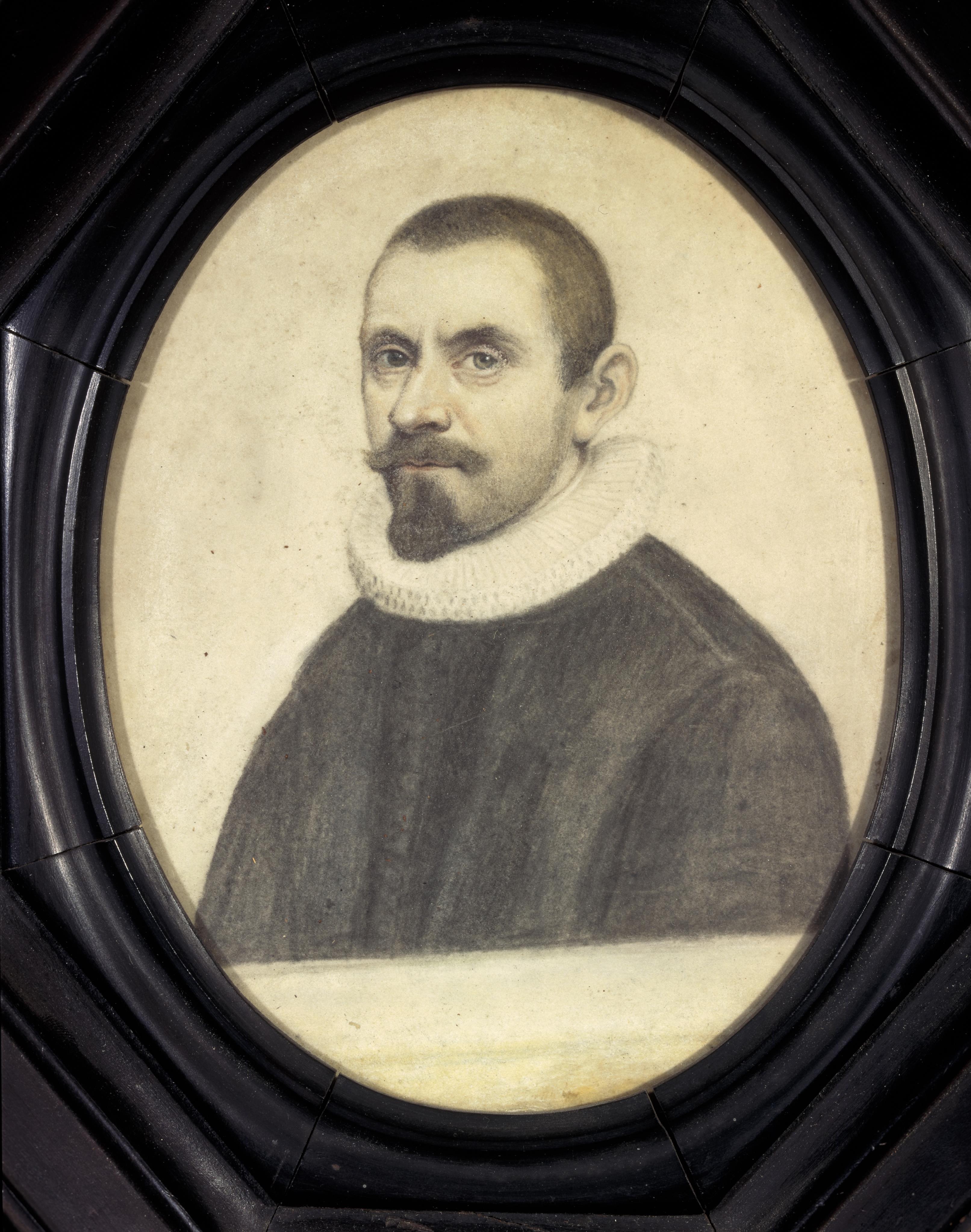 An oval portrait miniature of a man who looks out directly at the viewer. He wears black, with a white ruff at his collage. His hair is cut short above his pronounced ear, and he has a mustache and a beard that covers just his chin. The portrait is set in a simple black frame. 